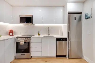 a kitchen with white cabinets and a stainless steel refrigerator at Spacious 1BDR unit with Private Patio and Parking by M11 in Montréal