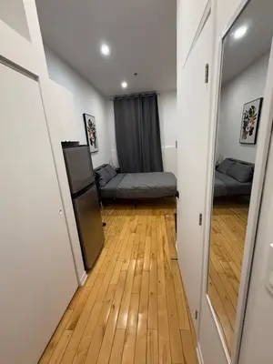a hallway with a room with two beds and a mirror at Cozy studio with Parking near downtown in Montréal