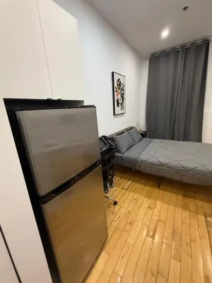 a kitchen with a refrigerator and a bed in a room at Cozy studio with Parking near downtown in Montréal