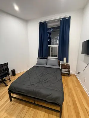 a bedroom with a large bed with blue curtains at Well located studio with Parking near Downtown Montreal in Montréal