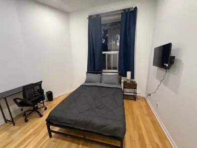 a bedroom with a bed and a window with blue curtains at Well located studio with Parking near Downtown Montreal in Montréal