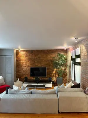 a living room with two large couches and a brick wall at Le Old World Meets Modern in Montréal