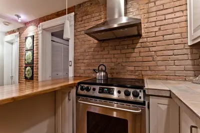 a kitchen with a stove and a brick wall at Le Old World Meets Modern in Montréal