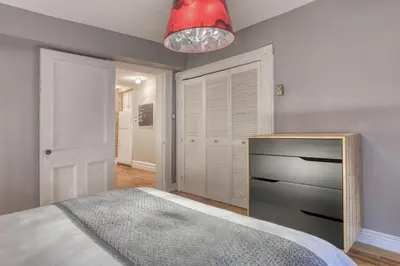 a bedroom with a bed with a dresser and a red lamp at Le Old World Meets Modern in Montréal