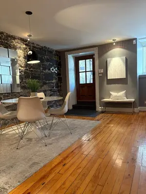 a living room with a table and chairs and a stone wall at Le Old World Meets Modern in Montréal