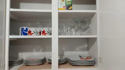 a white cabinet filled with plates and wine glasses at Spacious and comfortable accommodation in Longueuil