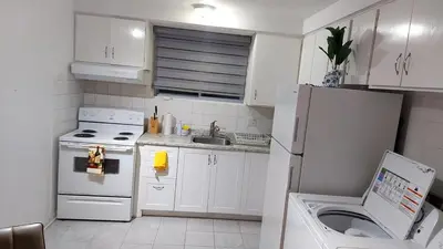 a kitchen with a white refrigerator and a sink at Spacious and comfortable accommodation in Longueuil