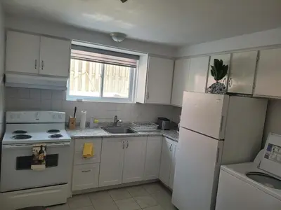 a kitchen with white cabinets and a white refrigerator at Spacious and comfortable accommodation in Longueuil