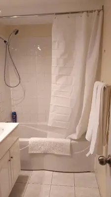 a white bathroom with a tub and a shower at Spacious and comfortable accommodation in Longueuil
