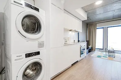 a white laundry room with two washer and dryer at Bright 1BR Apt with Convertible Armchair in Montréal