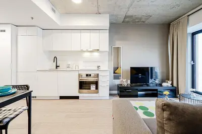 a kitchen with white cabinets and a living room at Bright 1BR Apt with Convertible Armchair in Montréal