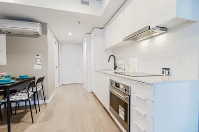 a kitchen with white cabinets and a dining table at Bright 1BR Apt with Convertible Armchair in Montréal