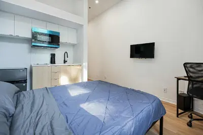 a bedroom with a blue bed and a kitchen at Beautiful 3 person 2 Beds Studio with parking near downtown Montreal in Montréal
