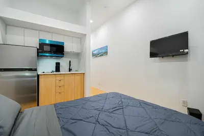 a kitchen with a refrigerator and a tv on the wall at Escape studio with parking near downtown Montreal in Montréal