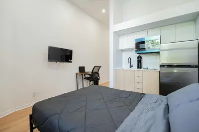 a bedroom with a bed and a kitchen with a refrigerator at Chic Bright Apartment with Parking Near downtown Montreal in Montréal