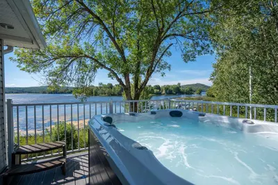 a hot tub on a balcony with a view of the water at Spa & Lake Access - Le Chic Shack des 3 lacs in Trois-Lacs
