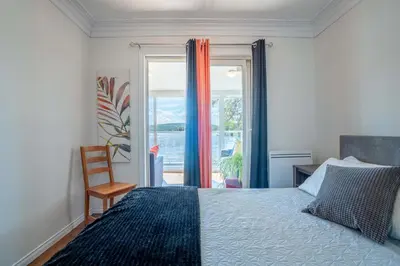 a bedroom with a bed and a chair and a window at Spa & Lake Access - Le Chic Shack des 3 lacs in Trois-Lacs