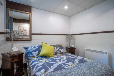 a bedroom with a blue bed and a mirror at Spa & Lake Access - Le Chic Shack des 3 lacs in Trois-Lacs