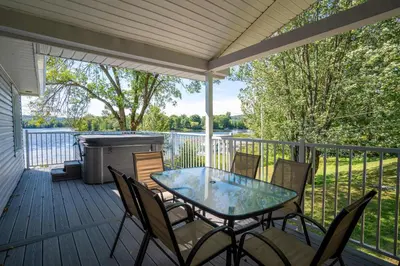 a screened porch with a table and chairs and a grill at Spa & Lake Access - Le Chic Shack des 3 lacs in Trois-Lacs