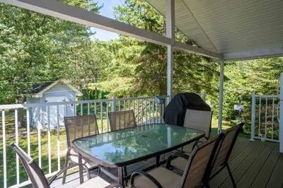 a screened porch with a glass table and chairs at Spa & Lake Access - Le Chic Shack des 3 lacs in Trois-Lacs