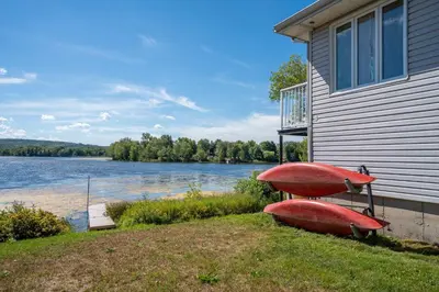 two boats sitting on the grass next to a house at Spa & Lake Access - Le Chic Shack des 3 lacs in Trois-Lacs
