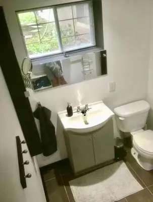 a bathroom with a toilet and a sink and a window at Appartement au calme, à 15 min de Montréal in Longueuil