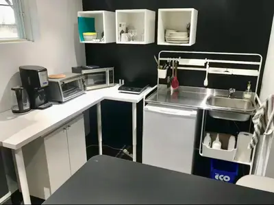 a small kitchen with white counters and a sink at Appartement au calme, à 15 min de Montréal in Longueuil