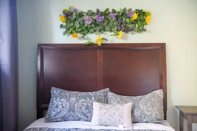 a bed with a wooden headboard with flowers on the wall at 3 bedrooms in Brossard,mins to REM station,hwy in Brossard