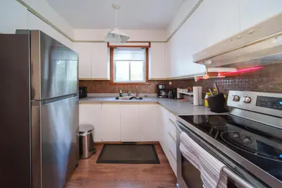 a kitchen with white cabinets and a stainless steel refrigerator at 3 bedrooms in Brossard,mins to REM station,hwy in Brossard