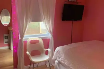 a bedroom with a bed and a chair and a window at House and treehouse near 2 ski resorts in Lac-Brome