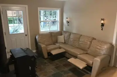 a living room with a couch and a table at House and treehouse near 2 ski resorts in Lac-Brome
