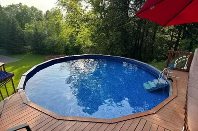 a swimming pool on a wooden deck with an umbrella at House and treehouse near 2 ski resorts in Lac-Brome