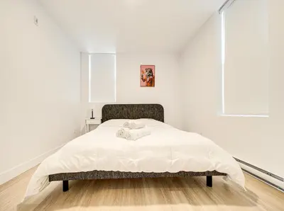 a white bedroom with a large bed with white sheets at Stunning 2 Bedroom Downtown Montreal in Montréal