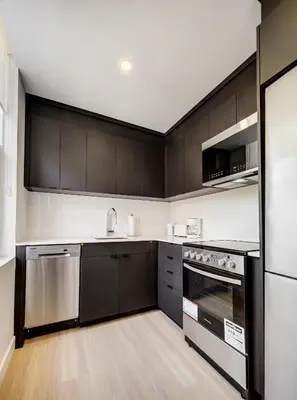 a kitchen with black cabinets and stainless steel appliances at Stunning 2 Bedroom Downtown Montreal in Montréal