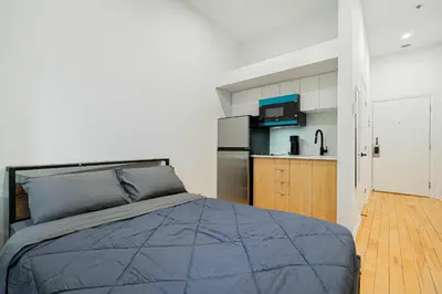a bedroom with a bed and a kitchen at Cozy Studio Near Downtown Montreal with Parking in Montréal