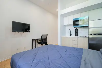 a bedroom with a blue bed and a kitchen at Cozy Studio Near Downtown Montreal with Parking in Montréal