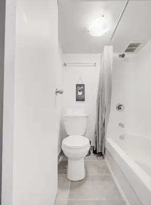 a white bathroom with a toilet and a bath tub at Elegant Studio in DT MTL AC, Wi-Fi in Montréal