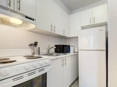 a kitchen with white cabinets and a white refrigerator at Elegant Studio in DT MTL AC, Wi-Fi in Montréal