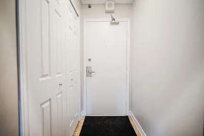 a hallway with a white door and a black rug at Downtown Montreal 2-Bedroom Gem near Bell Centre in Montréal