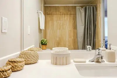 a bathroom counter with a sink and a mirror at Downtown Montreal 2-Bedroom Gem near Bell Centre in Montréal