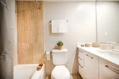 a bathroom with a toilet and a tub and a sink at Downtown Montreal 2-Bedroom Gem near Bell Centre in Montréal