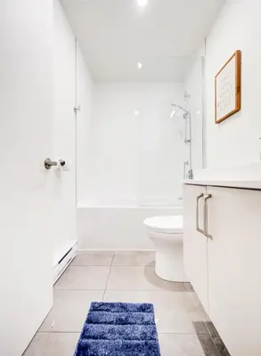 a bathroom with a toilet and a blue rug at Amazing 1Bed Downtown Mtl in Montréal