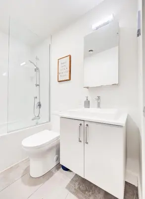 a white bathroom with a toilet and a sink at Amazing 1Bed Downtown Mtl in Montréal