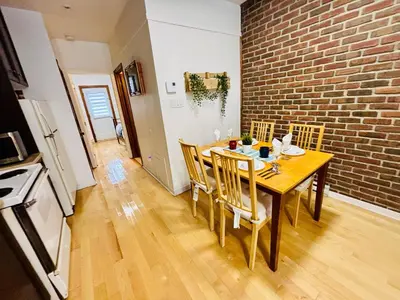 a dining room table with chairs and a brick wall at Sunrise Haven in Montréal