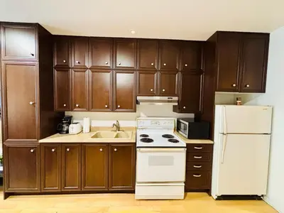 a kitchen with wooden cabinets and a white refrigerator at Sunrise Haven in Montréal