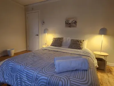 a bedroom with a large bed with a blue and white blanket at Chambre Zen, Résidence paisible près de Montréal in Longueuil