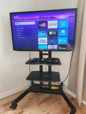 a flat screen tv sitting on a black stand at Chambre Zen, Résidence paisible près de Montréal in Longueuil