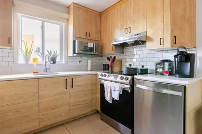 a kitchen with wooden cabinets and a stainless steel dishwasher at Verone 4 Appartement 4,5 Meublé 2ch Laval, Canada in Laval