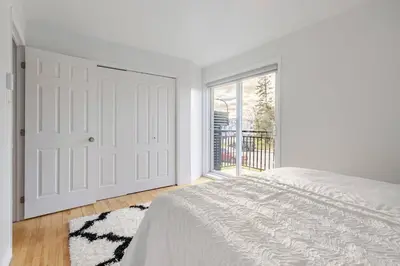 a white bedroom with a bed and a window at Verone 4 Appartement 4,5 Meublé 2ch Laval, Canada in Laval