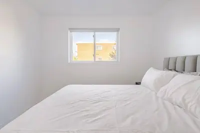 a white bed in a room with a window at Verone 4 Appartement 4,5 Meublé 2ch Laval, Canada in Laval